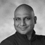 Black and white portrait of a smiling bald man looking directly at the viewer.