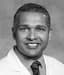 Headshot of a smiling professional man in a lab coat and striped tie.