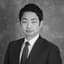 Black and white portrait of a young Asian man in a suit.