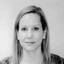 Black and white headshot of a woman with long hair looking directly at the viewer.