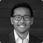 Smiling man with glasses in a black and white professional headshot.